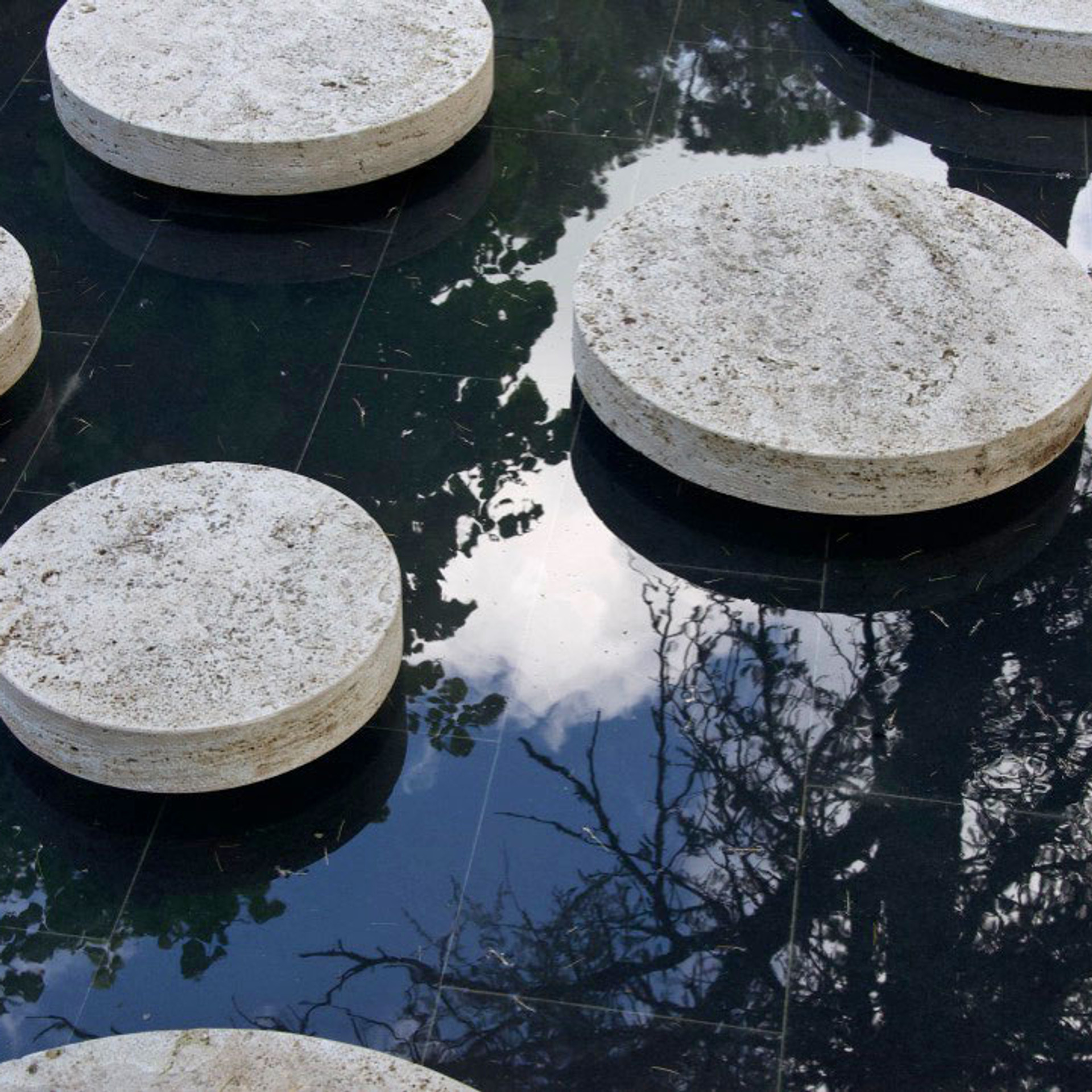 Dark reflecting pool with circular travertine stepping discs